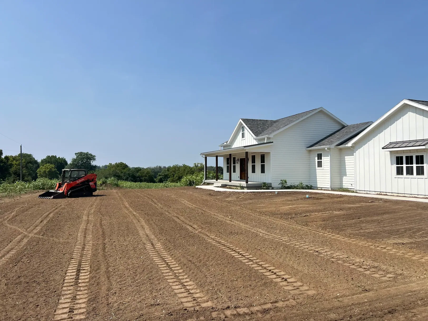 Compact track loader raking and grading a new home yard for seeding