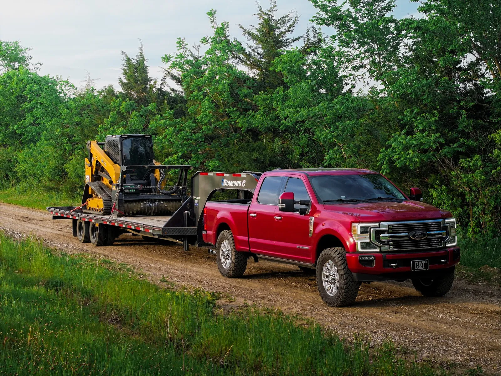 Red Ford truck pulling the mulcher on a Diamond C trailer