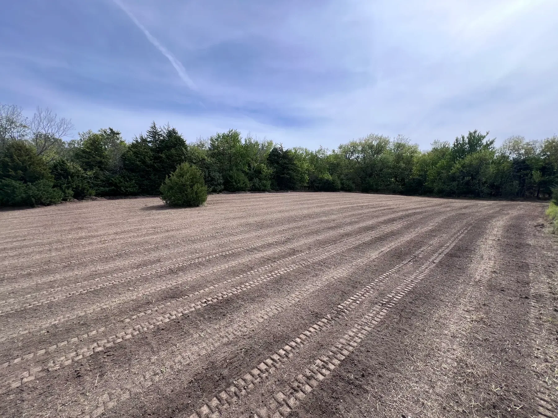 Wide finished graded field showing even track marks after leveling work