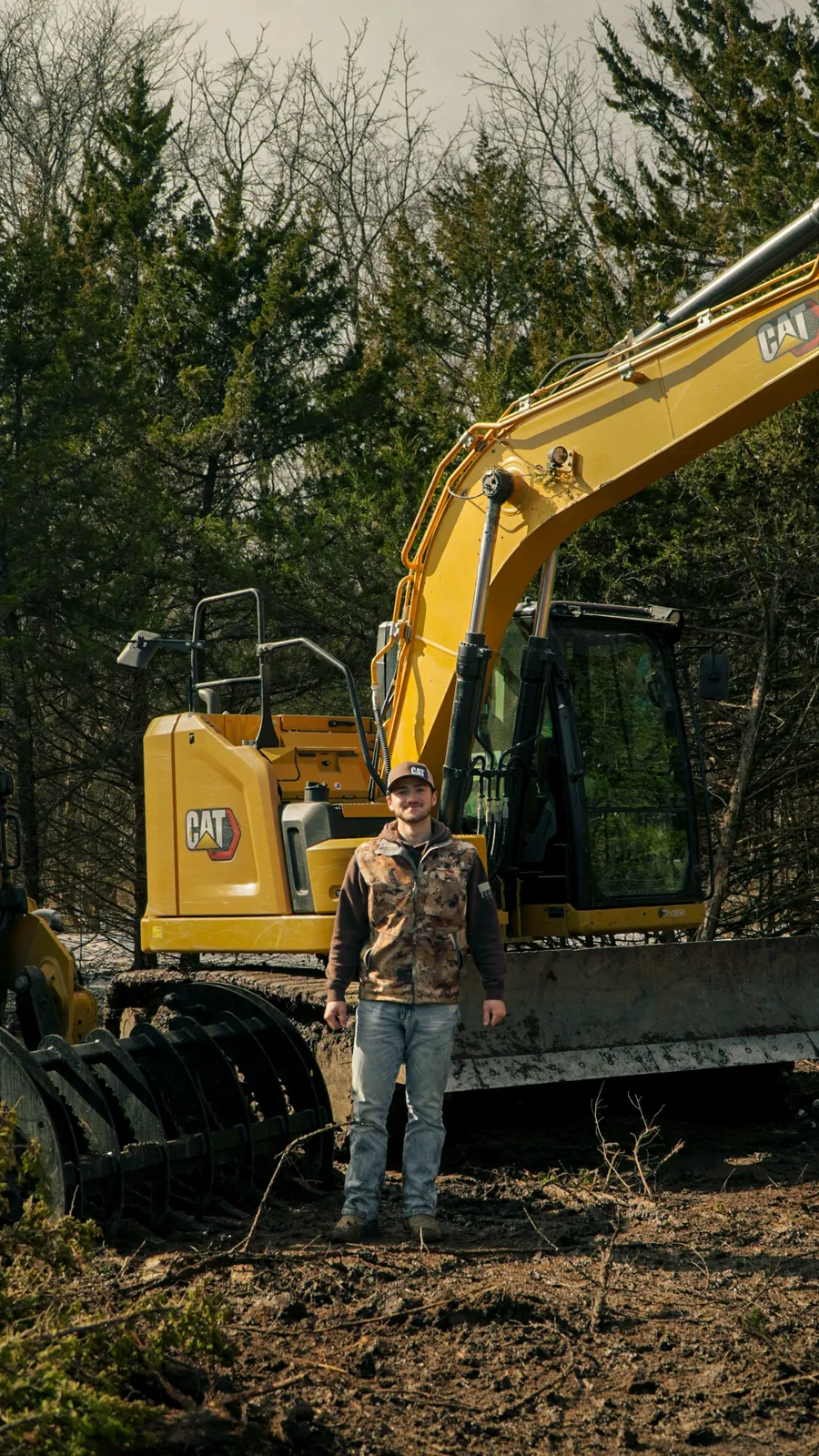 Ashton standing in front of the Grade A CAT excavator