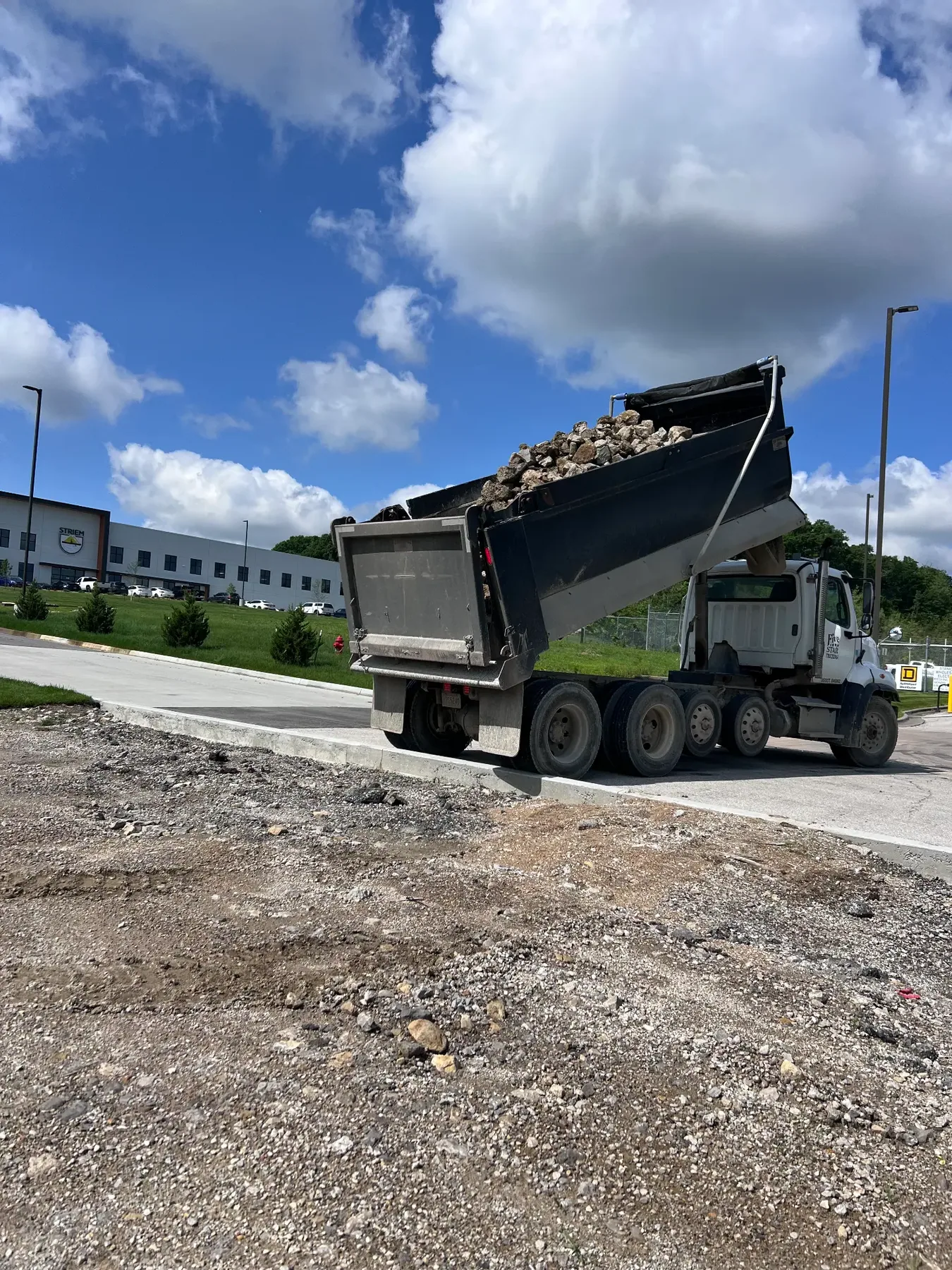 Dump truck delivering rock at a commercial site