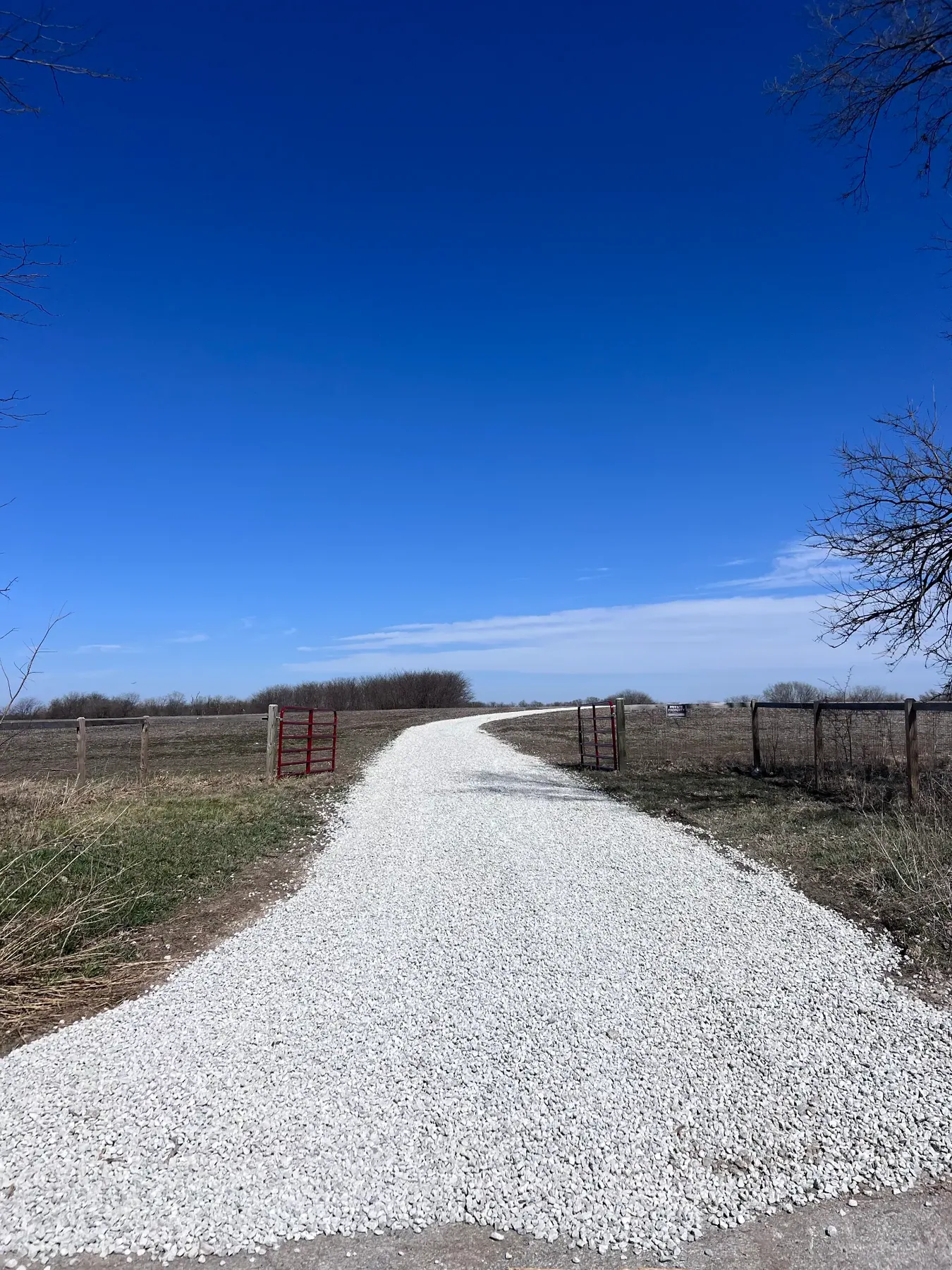 New white rock driveway leading through a gated rural entrance
