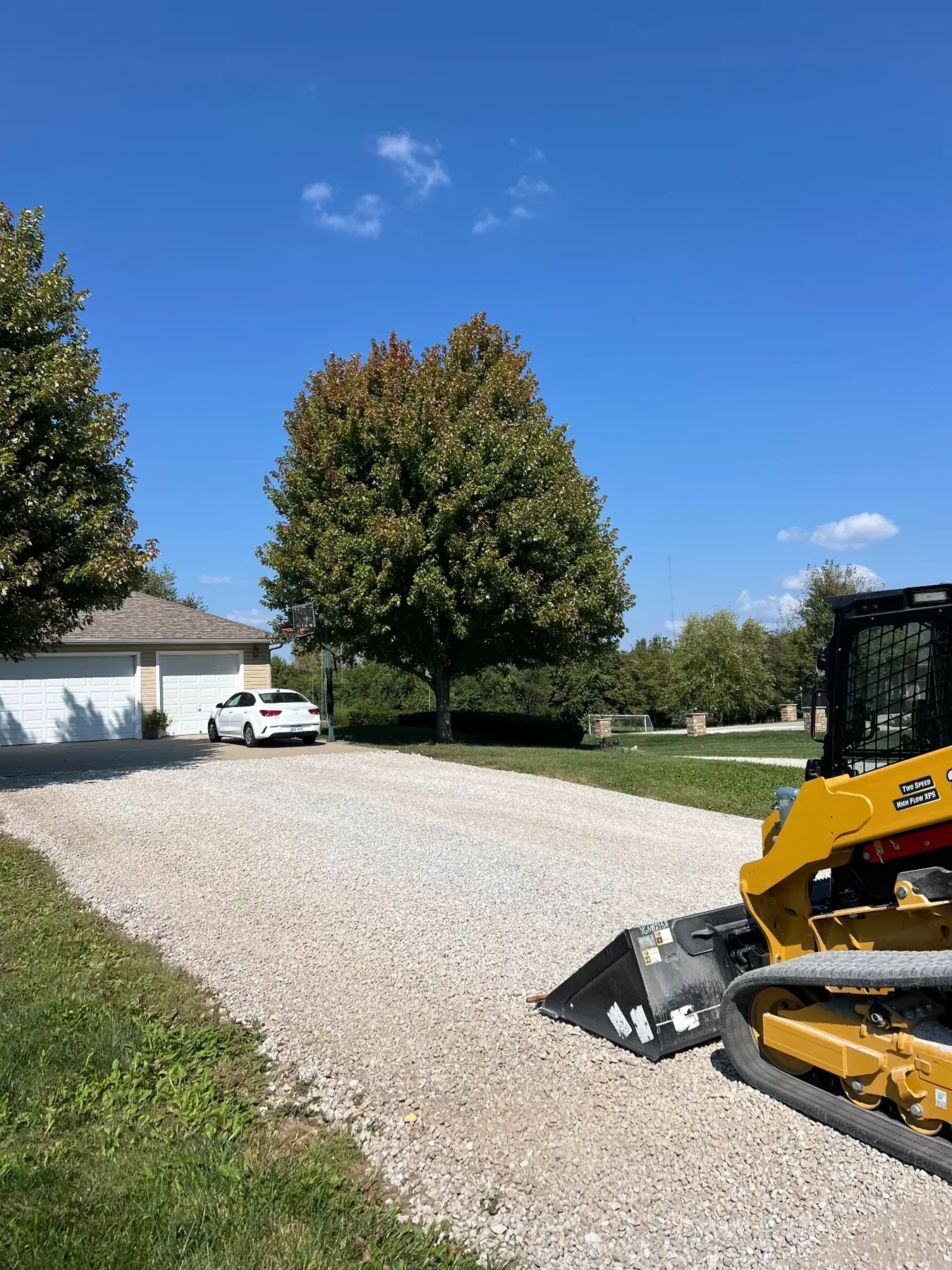 Finished white rock driveway with a CAT 265 track loader alongside