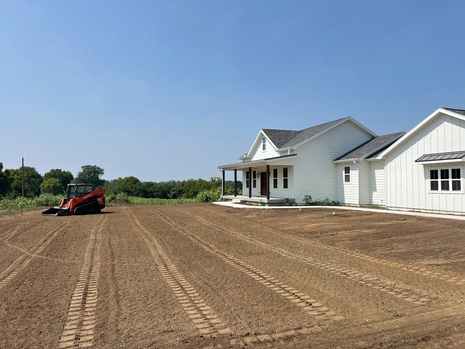 Freshly graded yard in front of a new white farmhouse
